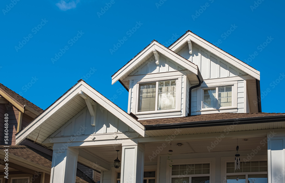 Top of a house with nice windows in the blue sky background. Beautiful Home Exterior. Real Estate Exterior Front House