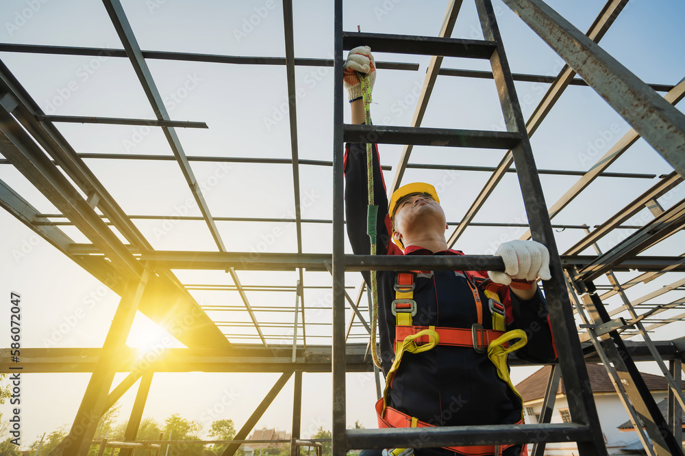 © Phoophinyo - Asian construction worker wearing safety body working at height factory roof steel structure