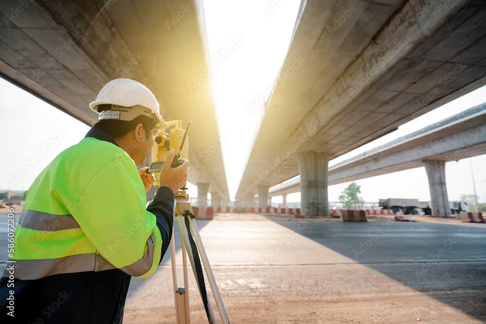Asian civil engineer surveying highway construction with theodolite Asian civil engineer surveying highway construction with theodolite
