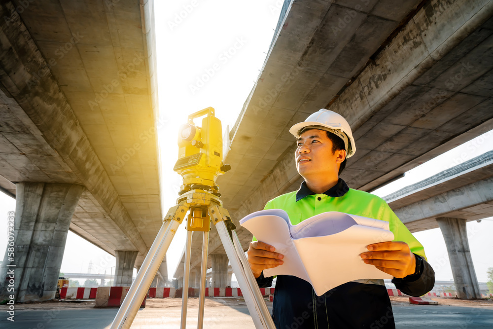 Asian civil engineer working with theodolite and highway construction ...