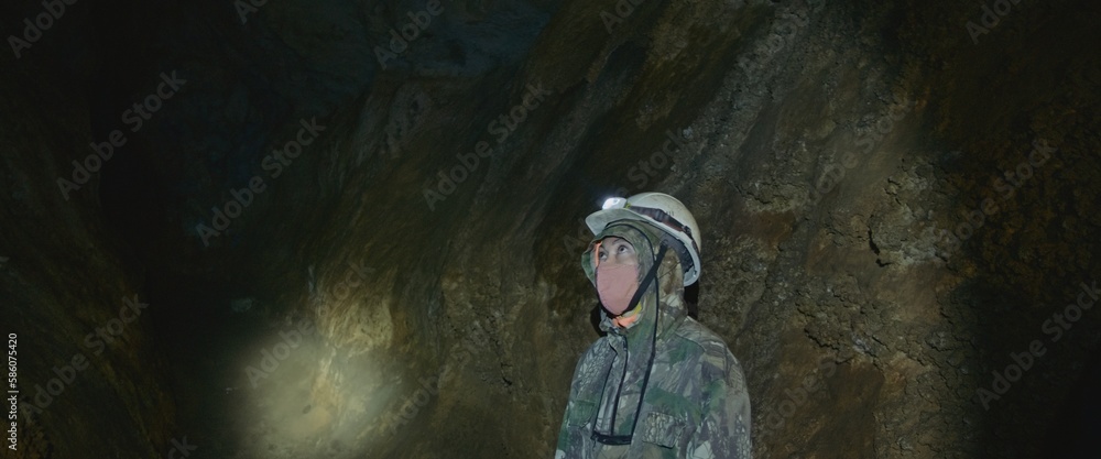 The cave excursion travel experience. The woman tourist marveled at the rock stone formations in the dark cavern. The cave tourism indoor.Its an attraction for adventure and nature lovers on any tour The cave excursion travel experience. The woman tourist marveled at the rock stone formations in the dark cavern. The cave tourism indoor.Its an attraction for adventure and nature lovers on any tour