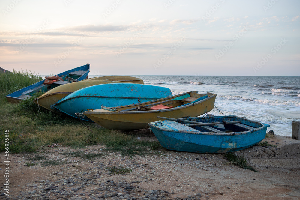 old overturned fishing boats on the seashore during sunset on the background of the sea.