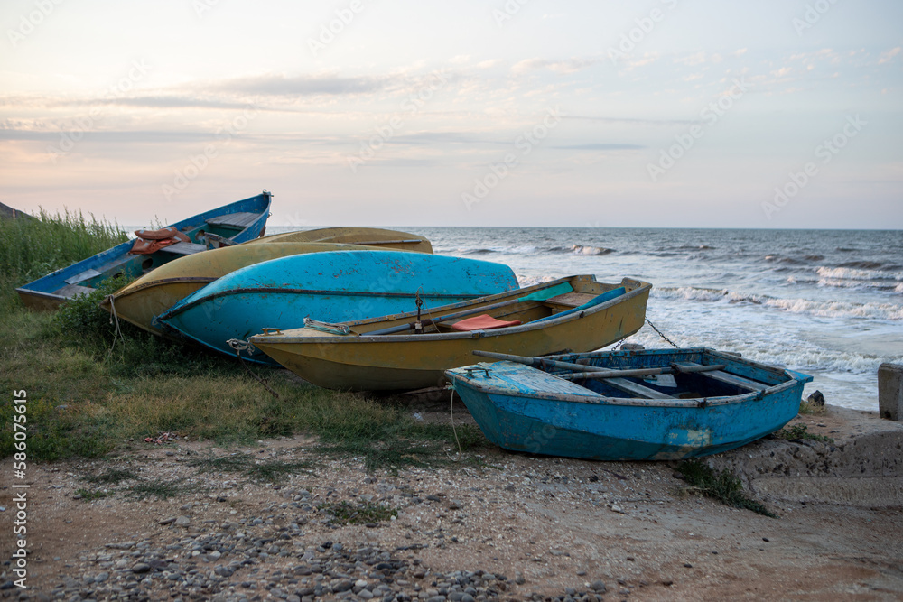 old overturned fishing boats on the seashore during sunset on the background of the sea. old overturned fishing boats on the seashore during sunset on the background of the sea.