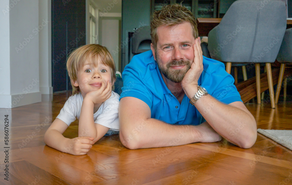 Fototapeta premium Parents and children being friends. Joyful father and son having fun, dad lying on floor. spending tim at home together. Single dad concept.