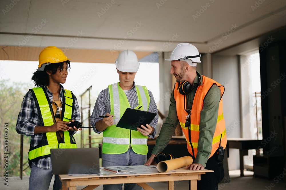 Contractor and architect looking at plan, tablet, laptop and talking about working on big project. Building in construction process interior. team work . Contractor and architect looking at plan, tablet, laptop and talking about working on big project. Building in construction process interior. team work .