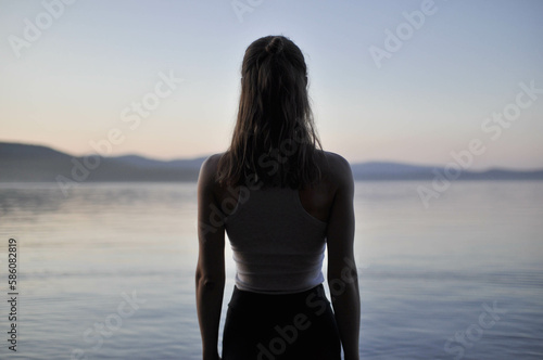 Serene solitude: Woman finds peace standing by mountain lake