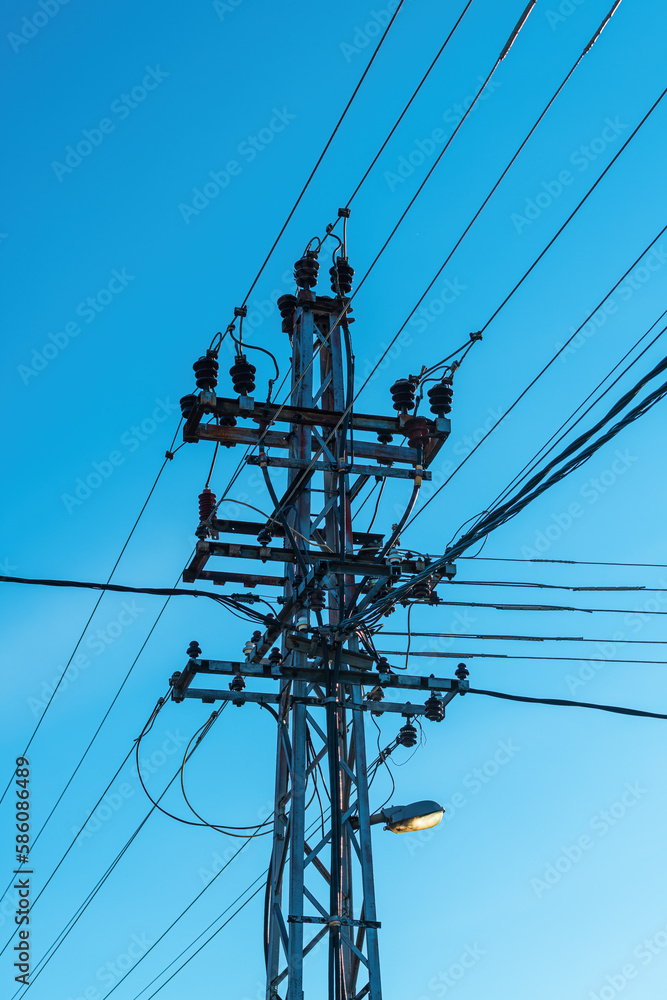 Old power utility and street light pole with cables and wires against blue sky Old power utility and street light pole with cables and wires against blue sky