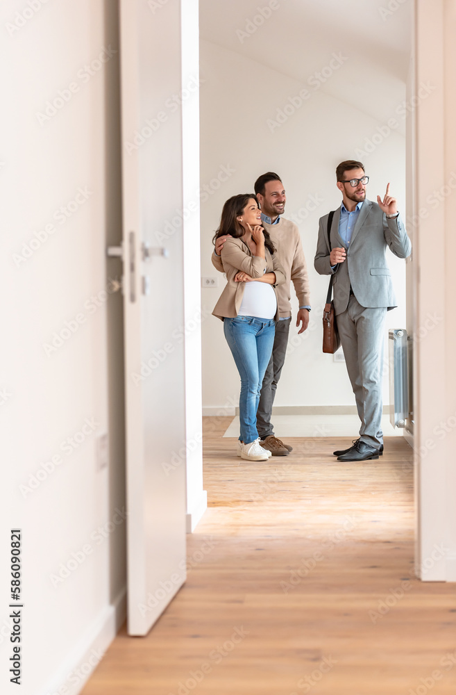 Young married couple talking with a real-estate agent visiting an apartment for sale or for rent. Future parents buying an apartment. Real estate concept. A new beginning Young married couple talking with a real-estate agent visiting an apartment for sale or for rent. Future parents buying an apartment. Real estate concept. A new beginning