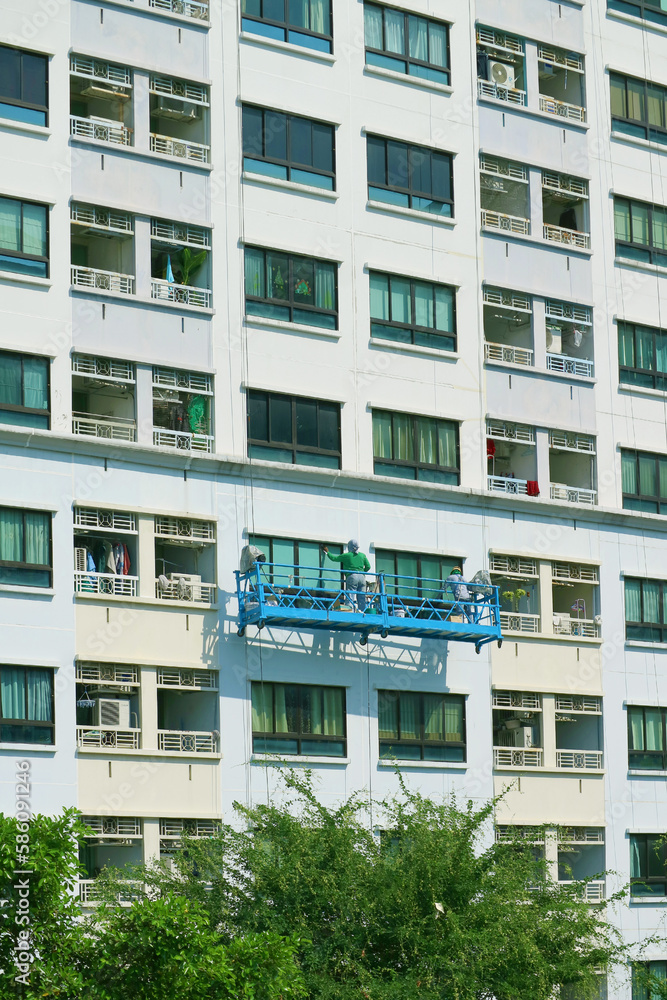 Two of rope access workers painting the facade of a high modern building