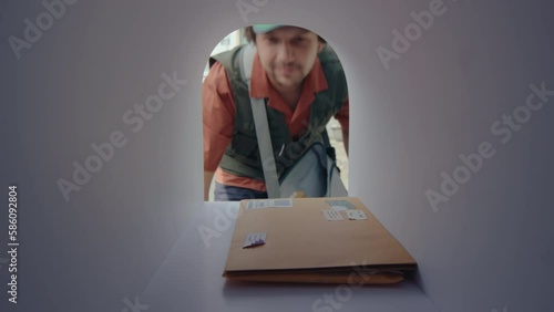 Young postman opening mailbox, placing a couple of letters inside, and then closing while delivering correspondence. POV shot from inside of the mailbox