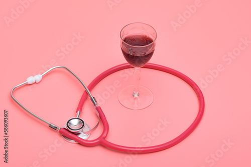 Kieliszek z winem i stetoskop na różowym tle