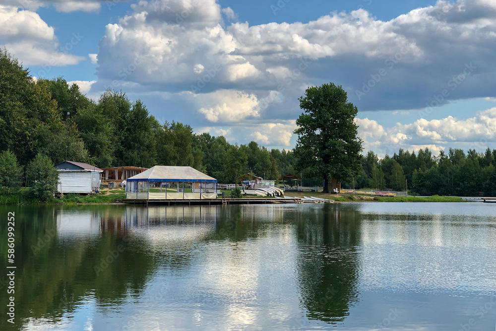 Obraz premium summer sunny day on bank of calm lake with gazebo near water edge
