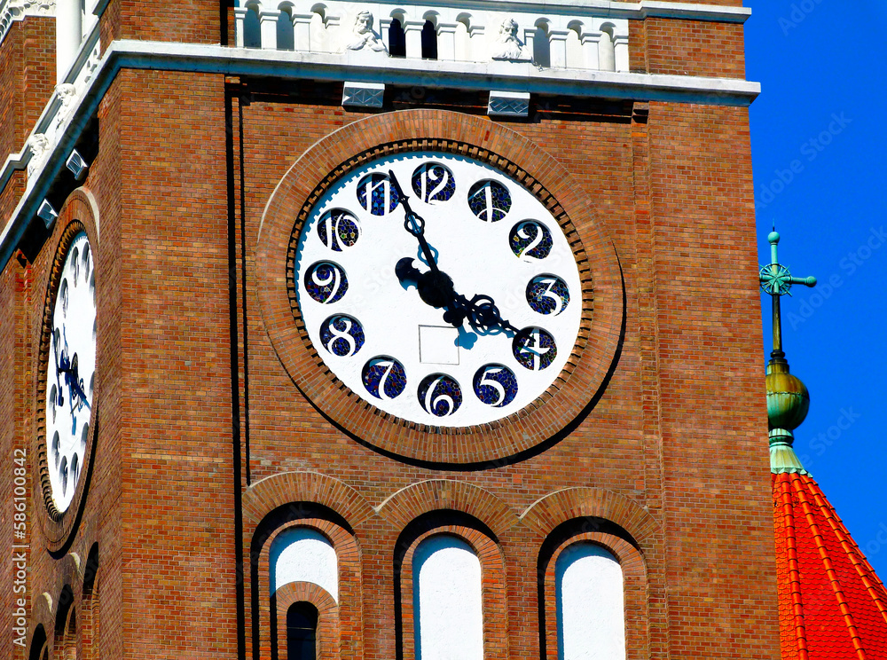church clock tower closeup detail with black hands. white clock face