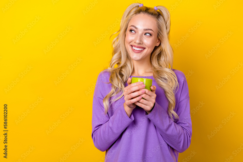 Photo portrait of lovely young lady hold coffee mug look empty space dressed stylish violet garment isolated on yellow color background Photo portrait of lovely young lady hold coffee mug look empty space dressed stylish violet garment isolated on yellow color background