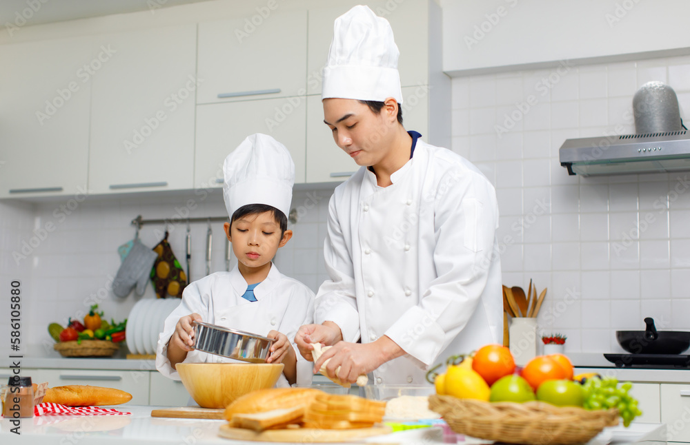 Asian young little boy pastry chef in white uniform with tall cook hat standing using stainless filter preparing sifting flour on wooden board while male cooking teacher helping teaching in kitchen Asian young little boy pastry chef in white uniform with tall cook hat standing using stainless filter preparing sifting flour on wooden board while male cooking teacher helping teaching in kitchen