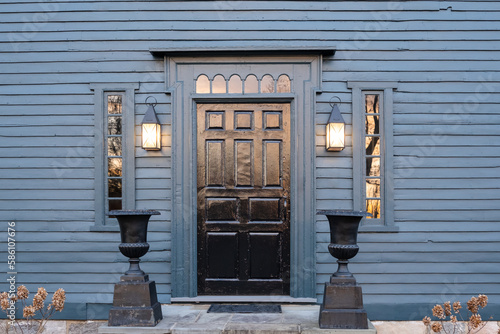 A wooden door on a blue colonial American house with sunset light