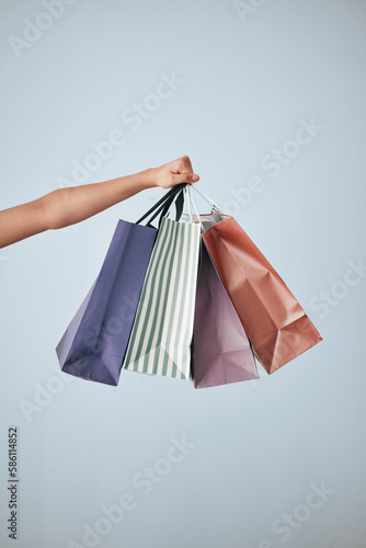 Hands, shopping bags and purchase in studio sale, discount or fashion against a gray background. Hand of shopper holding bag of buying gifts, present or luxury retail products or items on copy space