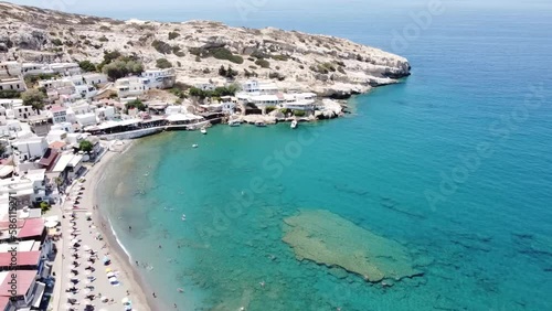 Aerial drone view of famous Matala beach with caves, known for hippies in the 70's. View of the beach from rock caves, once a roman cemetery, in famous greek beach Matala, Crete, Greece.