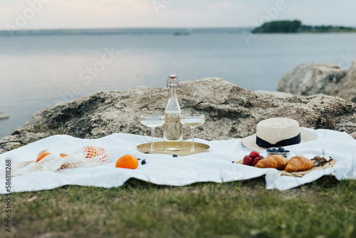 Concept of summer delicious picnic on the rocky hill with amazing view on the sea. Beautiful summer picnic with berries, wine and croissants.