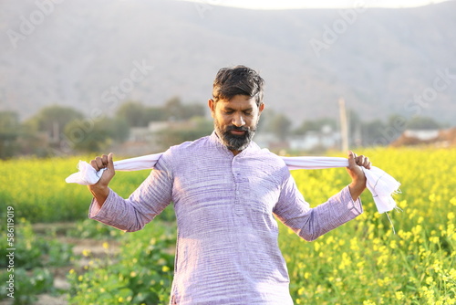 Happy rural Indian farmer enjoying the wind while stretching his scarf behind his neck. © Maahir