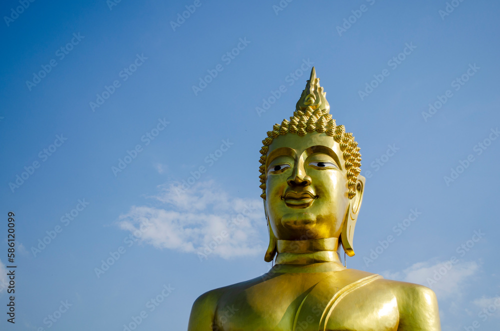 Head of the Big Buddha statue against a blue clear sky, copy space