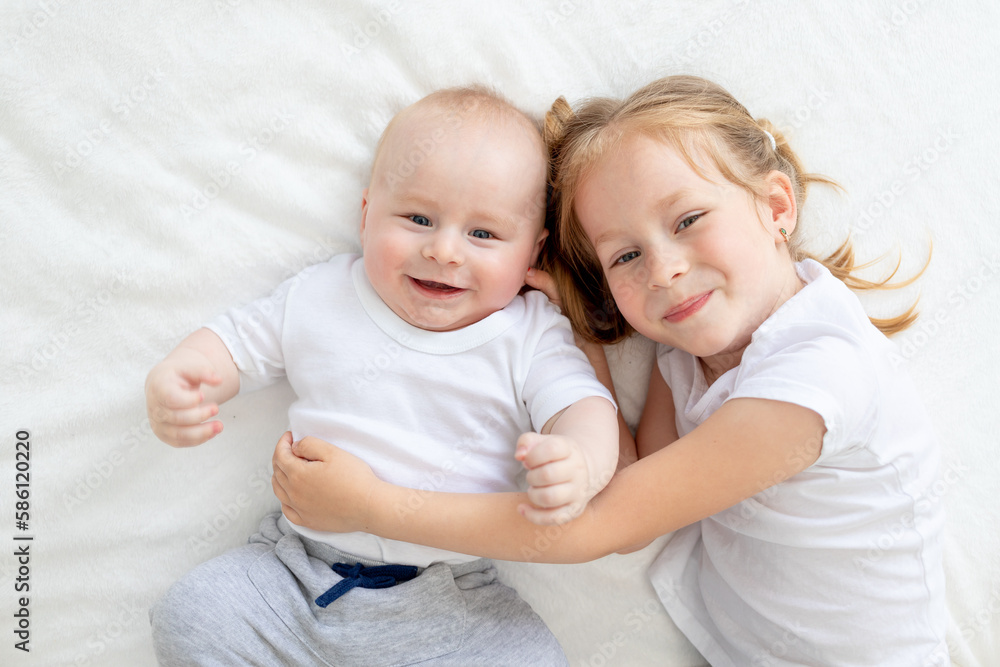 sister hugs little brother on the bed and smiles sister hugs little brother on the bed and smiles