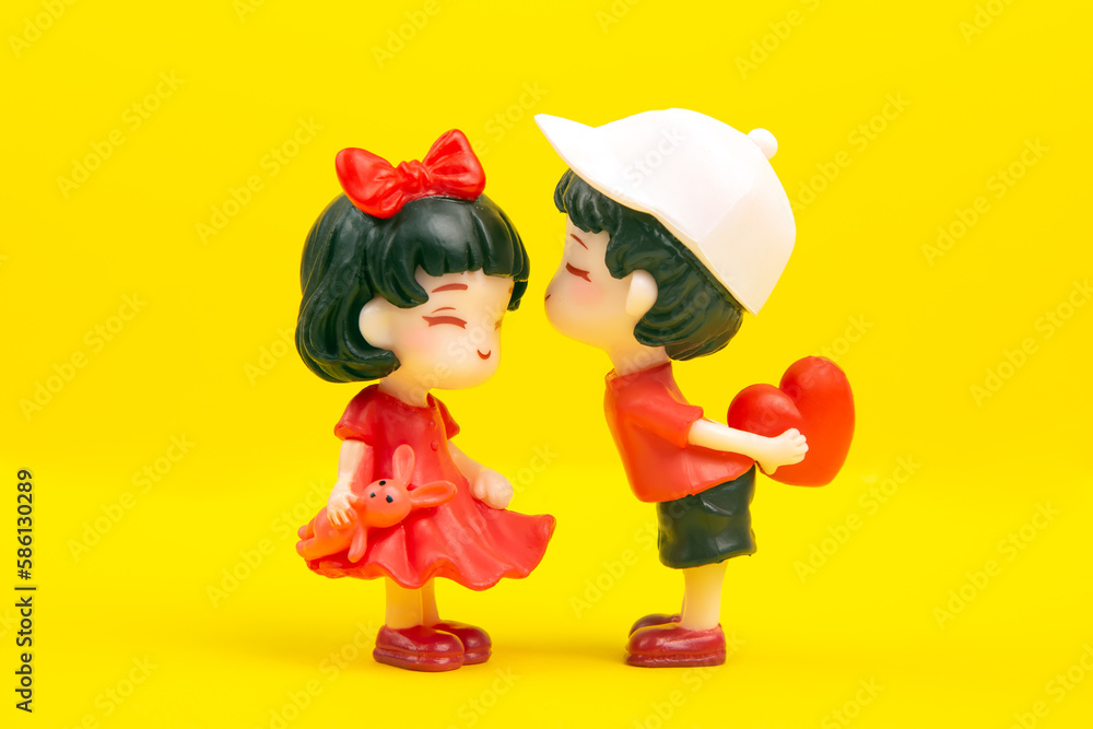 Fototapeta premium miniature people. figures for the game. romantic couple of young people. A boy lovingly gives his heart to a cute girl