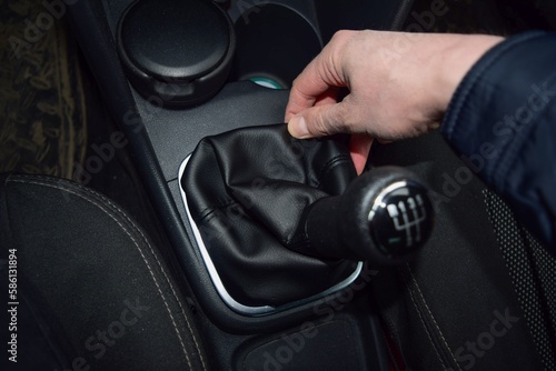 The driver's hand installs a new leather case on the gear lever in the car