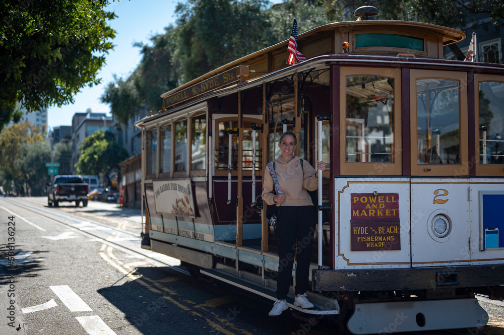 Naklejka premium Portrait of a young blonde tourist girl boarding the San Francisco Cable Car