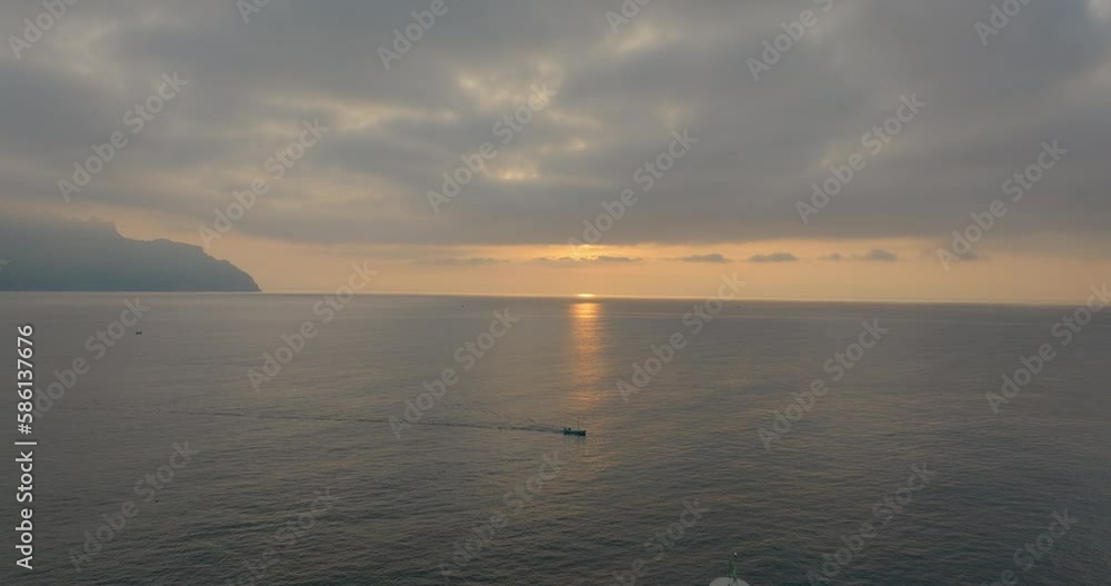 Aerial Panning Shot Of Nautical Vessel Moving On Rippled Sea By Hotels On Mountain Under Clouds During Sunset - Amalfi, Italy Aerial Panning Shot Of Nautical Vessel Moving On Rippled Sea By Hotels On Mountain Under Clouds During Sunset - Amalfi, Italy