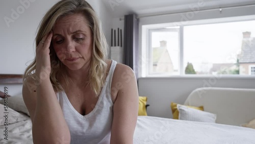 Menopausal Mature Woman Suffering With Low Mood And Anxiety Sitting On Bed At Home 