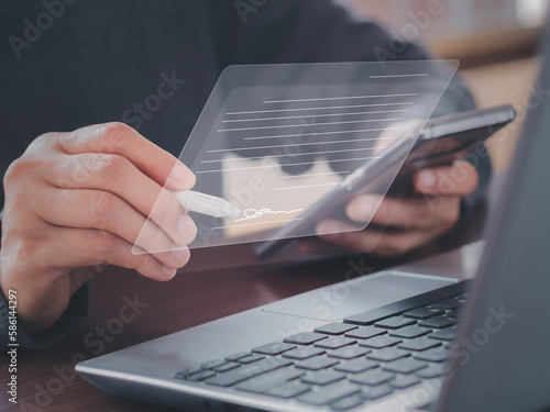 Electronic signature concept. Businessman signs electronic documents on virtual laptop screen using stylus pen. E-signing, digital document management, paperless office, signing business contract. . photo