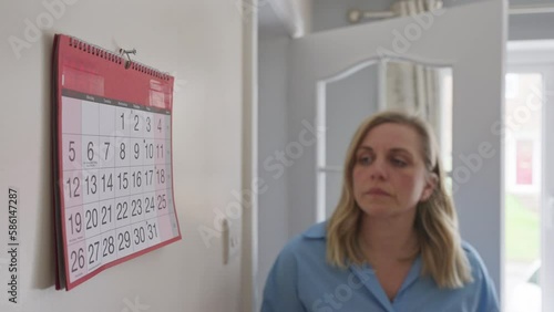 Menopausal Mature Woman With Poor Memory Looking At Calendar At Home