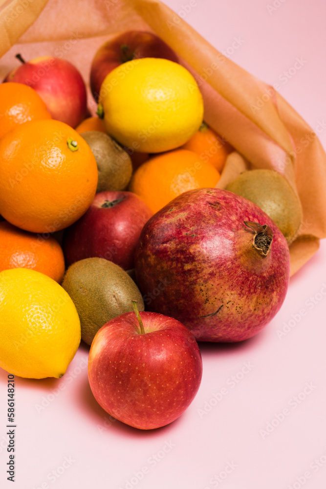 Fruits in a reusable bag on a pink background, pomegranate fruit, kiwi, lemon and apple close-up. Earth day and zero waste concept. Fruits in a reusable bag on a pink background, pomegranate fruit, kiwi, lemon and apple close-up. Earth day and zero waste concept.