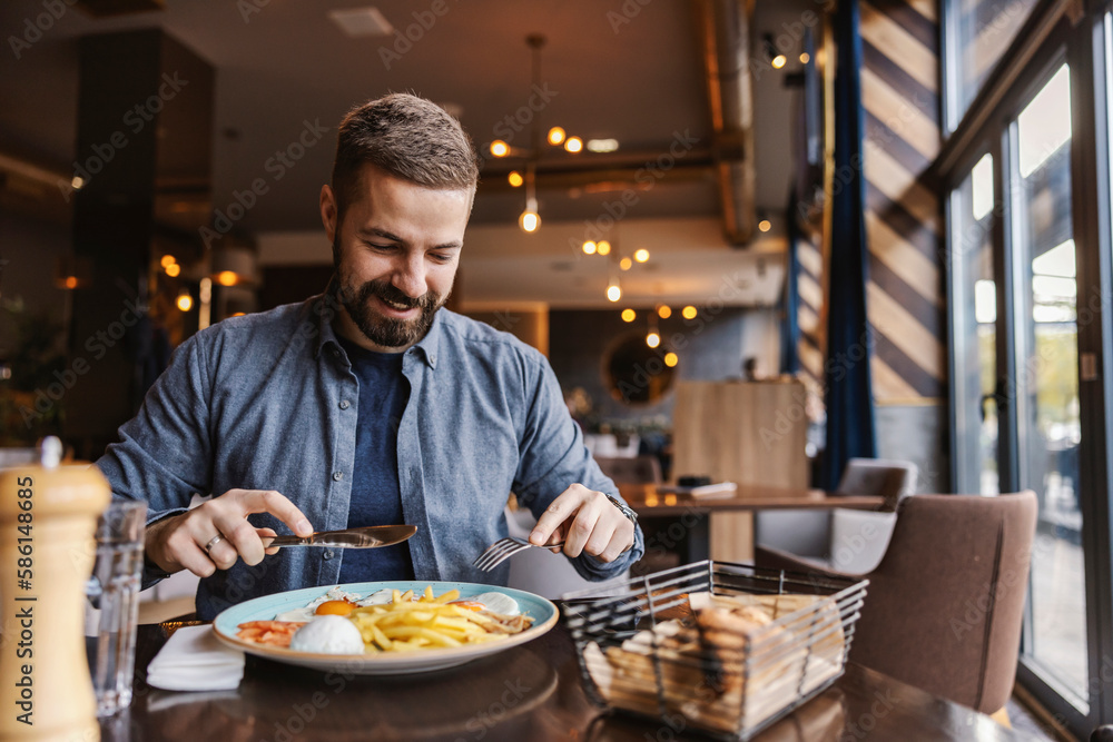 A hungry young man is sitting in a restaurant and having eggs for breakfast. A hungry young man is sitting in a restaurant and having eggs for breakfast.