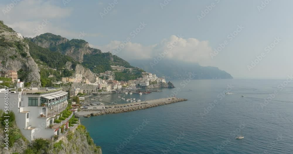 Aerial Forward Shot Of Nautical Vessels Moored At Harbor By Mountains Against Cloudy Sky - Amalfi, Italy Aerial Forward Shot Of Nautical Vessels Moored At Harbor By Mountains Against Cloudy Sky - Amalfi, Italy