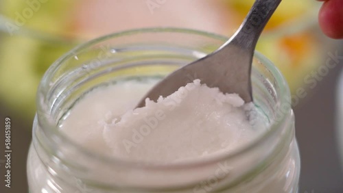 Spooning coconut oil in a glass jar for cooking dietary food. Close up photo