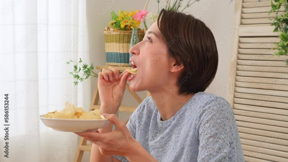 家でポテトチップスを食べる女性