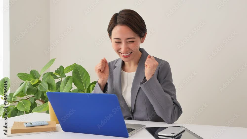 オフィスでノートパソコンを見て喜ぶビジネスウーマン