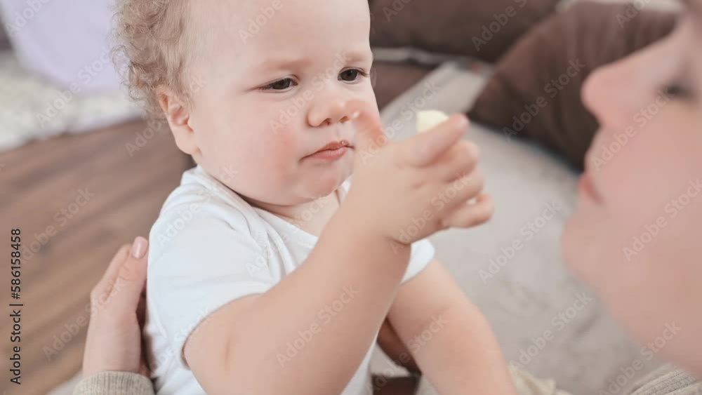 the baby eats cheese in his mother's arms. hands mom cheese, slow motion the baby eats cheese in his mother's arms. hands mom cheese, slow motion