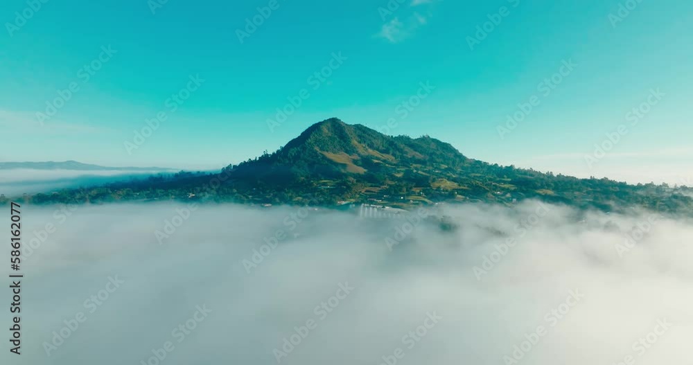 High mountain surrounded by clouds at sunset. Cinematic drone aerial shot. pan from bottom to top. High mountain surrounded by clouds at sunset. Cinematic drone aerial shot. pan from bottom to top.