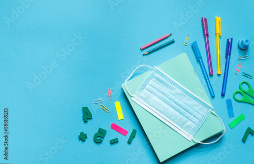 back to school.school supplies for study, notebooks and colored pens and a protective mask on a blue background, with space for text.