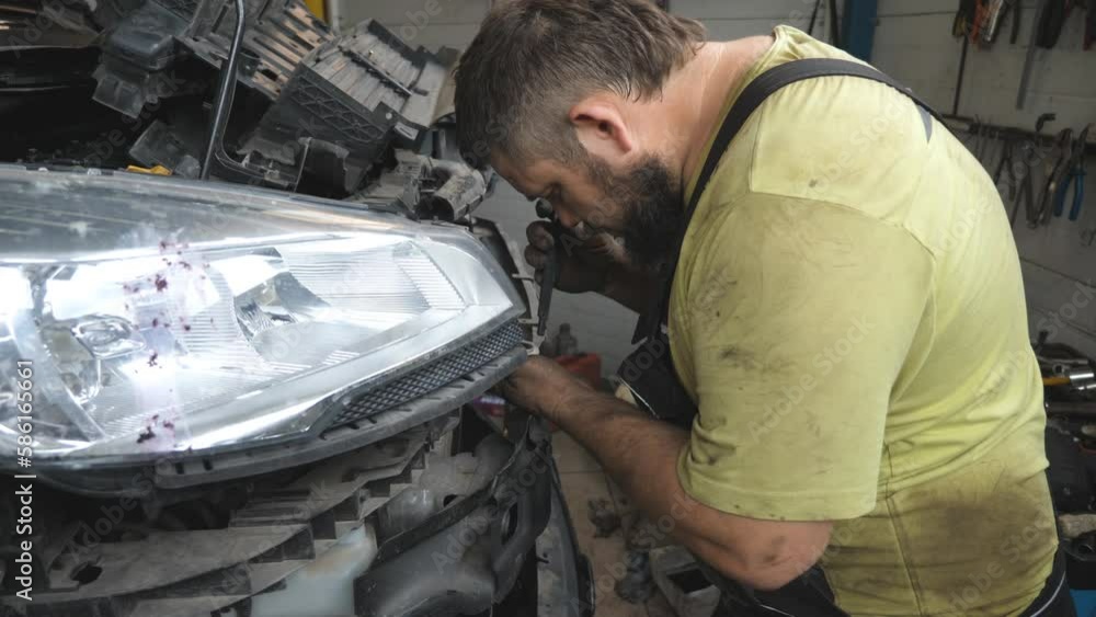 Professional bearded repairman fixing car with open hood at workshop. Auto mechanic in uniform working with vehicle at garage. Concept of automobile maintenance and diagnostic. Slow motion Close up Professional bearded repairman fixing car with open hood at workshop. Auto mechanic in uniform working with vehicle at garage. Concept of automobile maintenance and diagnostic. Slow motion Close up