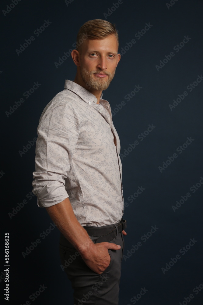 Blonde young man standing confident, portrait on studio background. Business, couch, office concept
