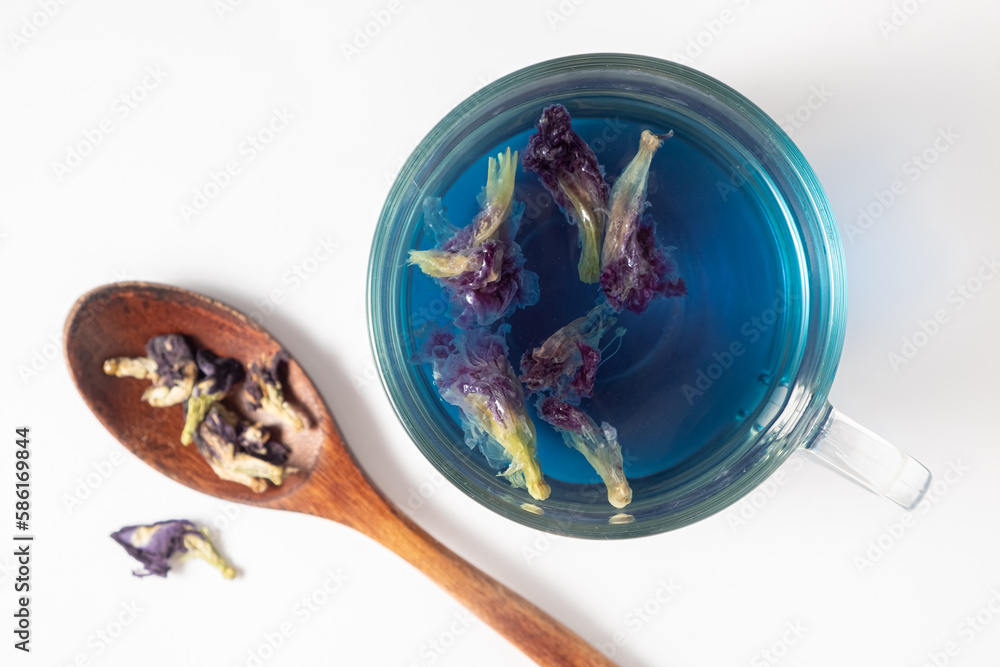 Chinese blue anchan tea in a glass cup and wooden spoon on a white background. Top view, Selective focus Chinese blue anchan tea in a glass cup and wooden spoon on a white background. Top view, Selective focus