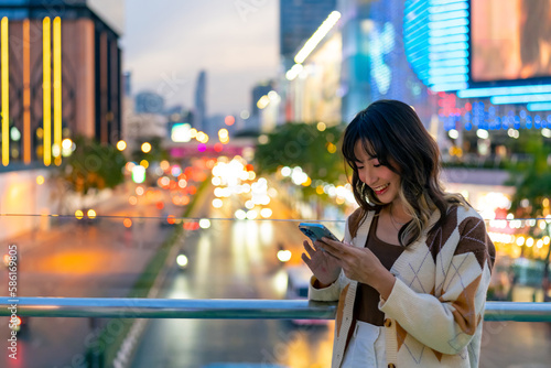 Photo Young Asian woman using smartphone for social media or online chat message in the city at night