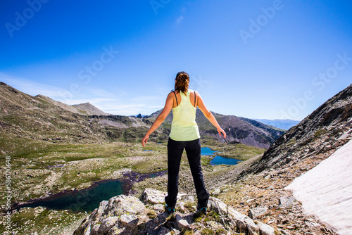Young hiker girl standing on top of the mountain and enjoying valley view in La Cerdanya, Pyrenees, Spain