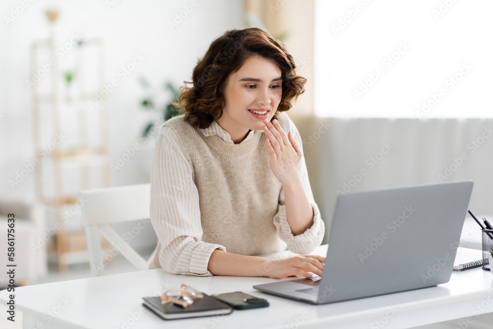 cheerful and young teacher showing thank you gesture during online lesson on laptop.