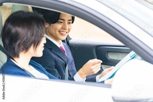 Bild auf Leinwand 女性に運転を指導する男性　自動車教習所　試乗車　カーディーラー