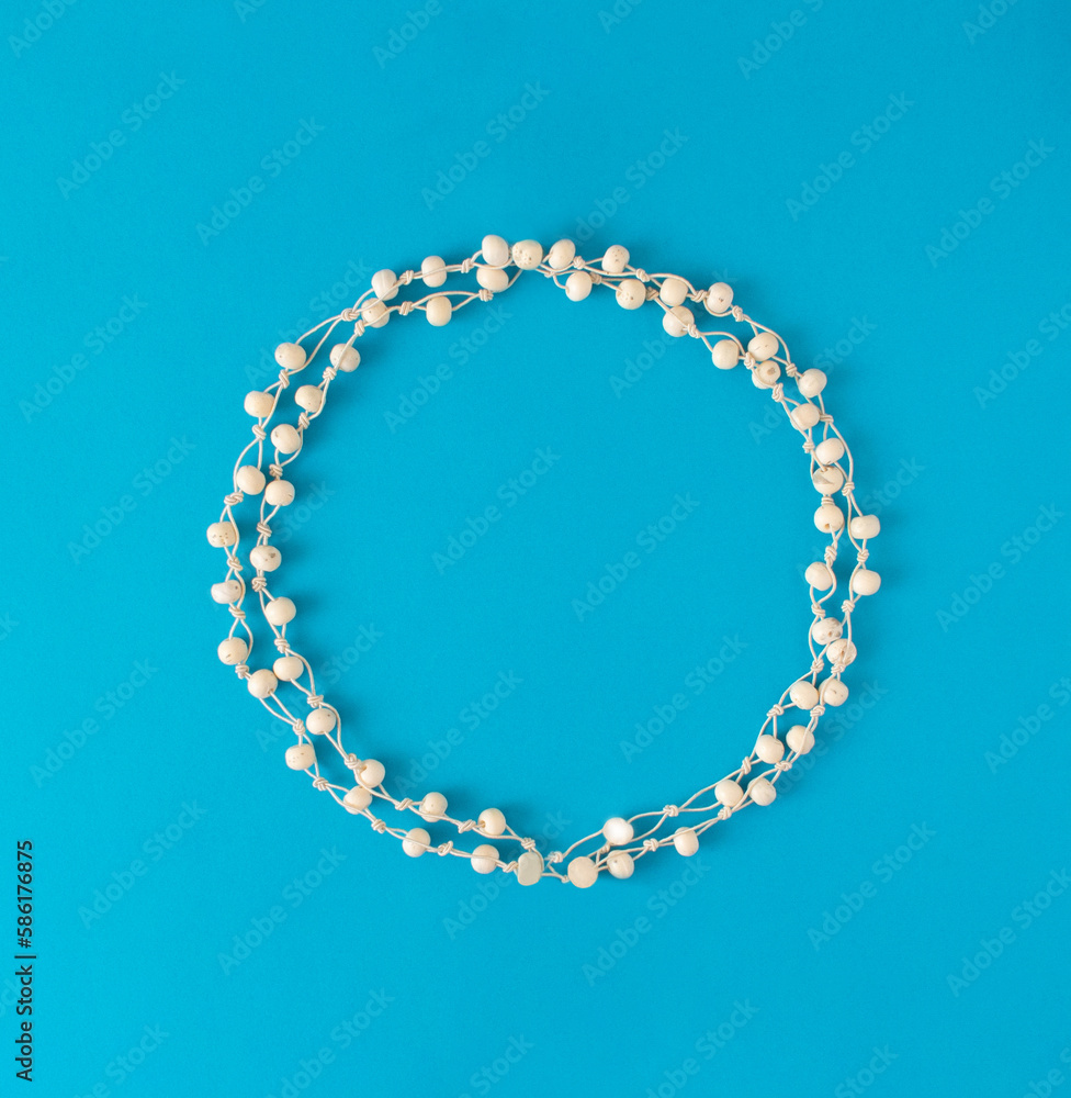 Obraz premium Beautiful round frame of white pearls. White circle on blue background.. Flat lay concept.